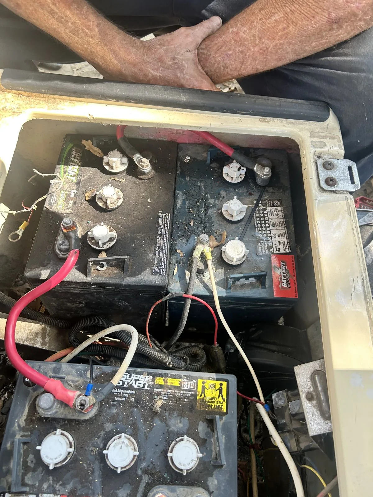 Golf cart battery bay with the seat lifted, three lead-acid batteries and their cables exposed for testing at Built Different Cart Co, Quinlan TX