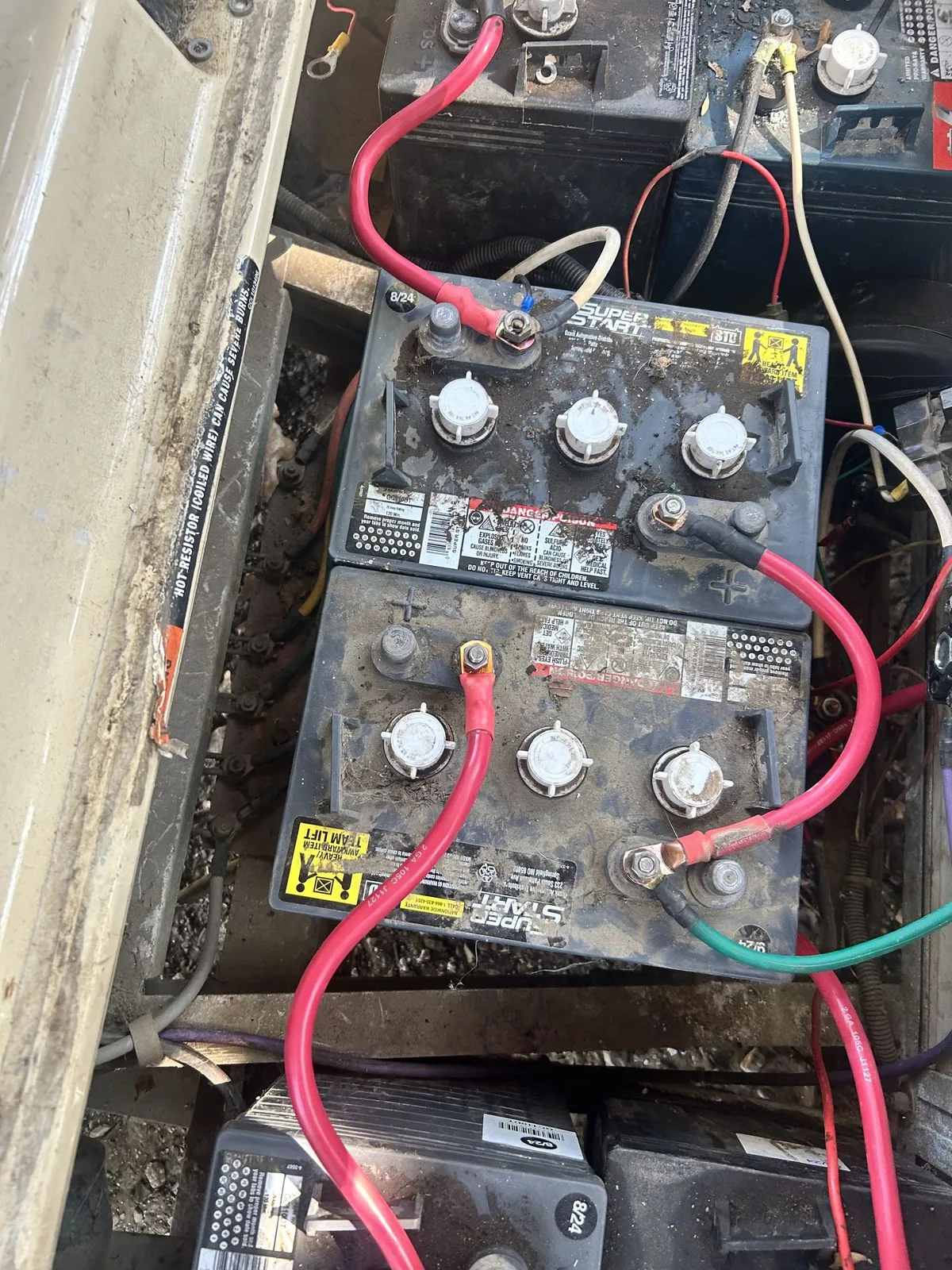 Golf cart battery pack seen from above with the seat lifted, Super Start batteries with red and green cables on the terminals, at Built Different Cart Co, Quinlan TX